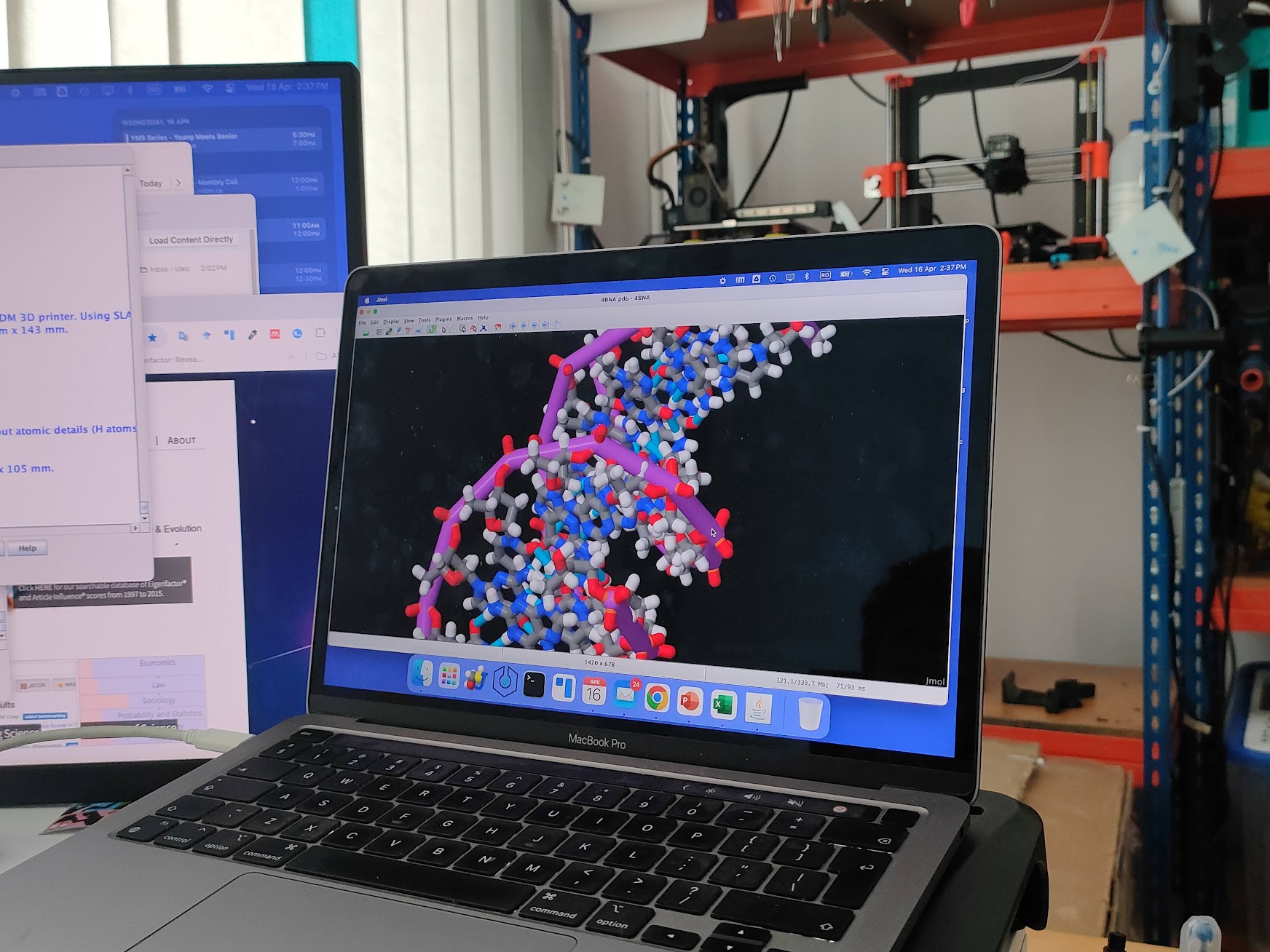 MacBook care afișează un model molecular 3D în Jmol, lângă o imprimantă 3D în laboratorul lui Marius Mihășan